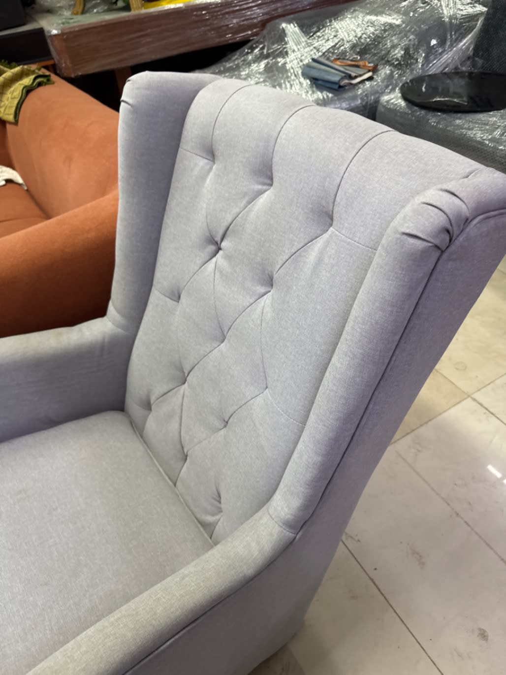 Close-up of tufted back on used light grey wingback rocking armchair at Bufaisal Ajman