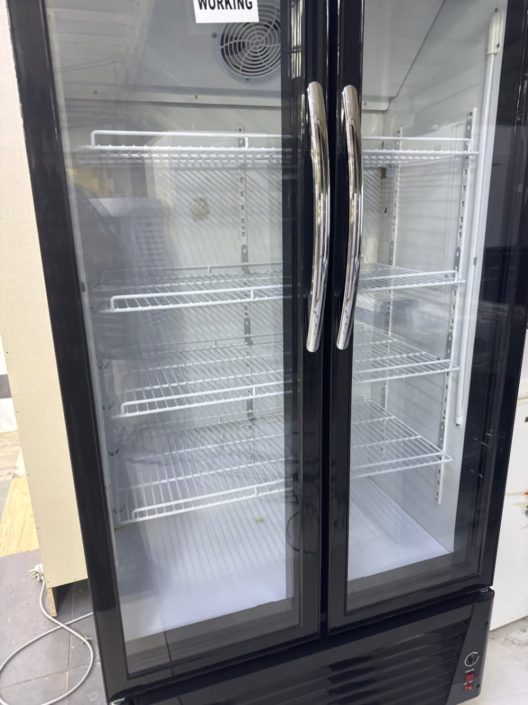 Interior close-up of used Terim display refrigerator showing adjustable wire shelves and fan unit