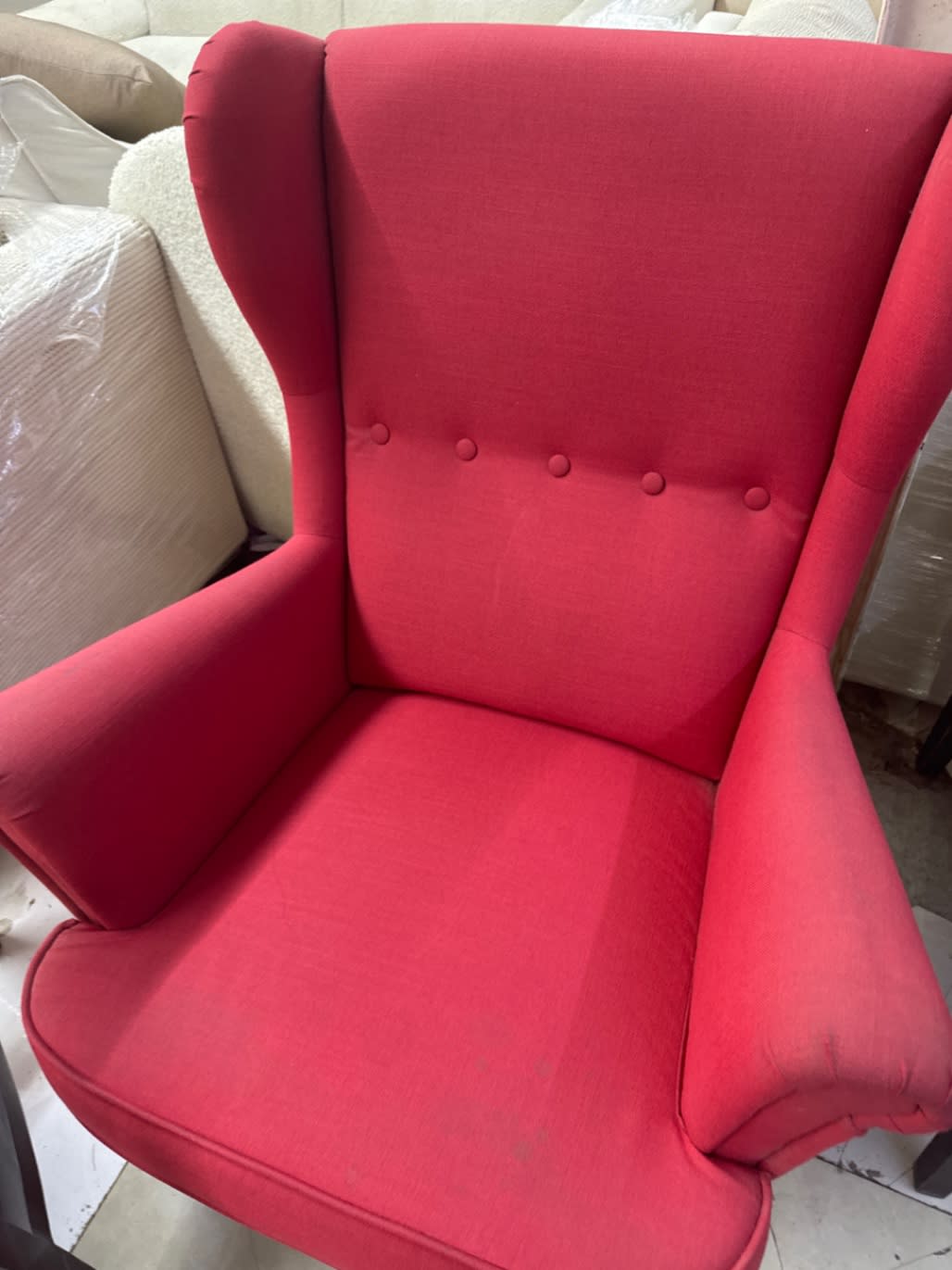 Close-up of seat and back of used red wingback armchair showing light wear on fabric