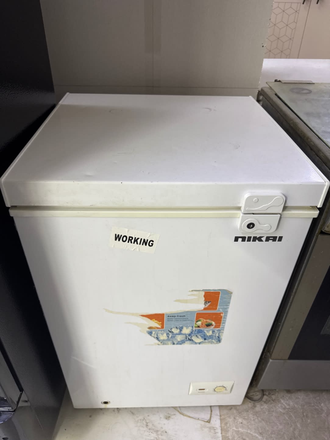 Front view of used Nikai white chest freezer showing exterior scuffs and peeled sticker