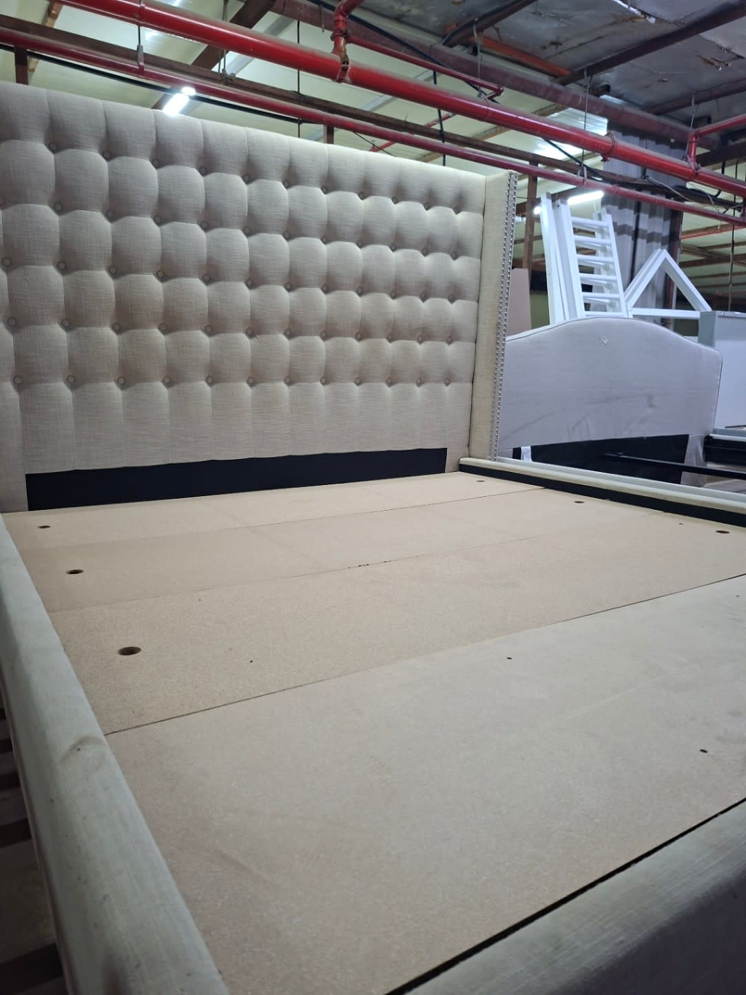 Side-angle view of used king bed frame 180x200 beige upholstered platform base at Bufaisal Shop D