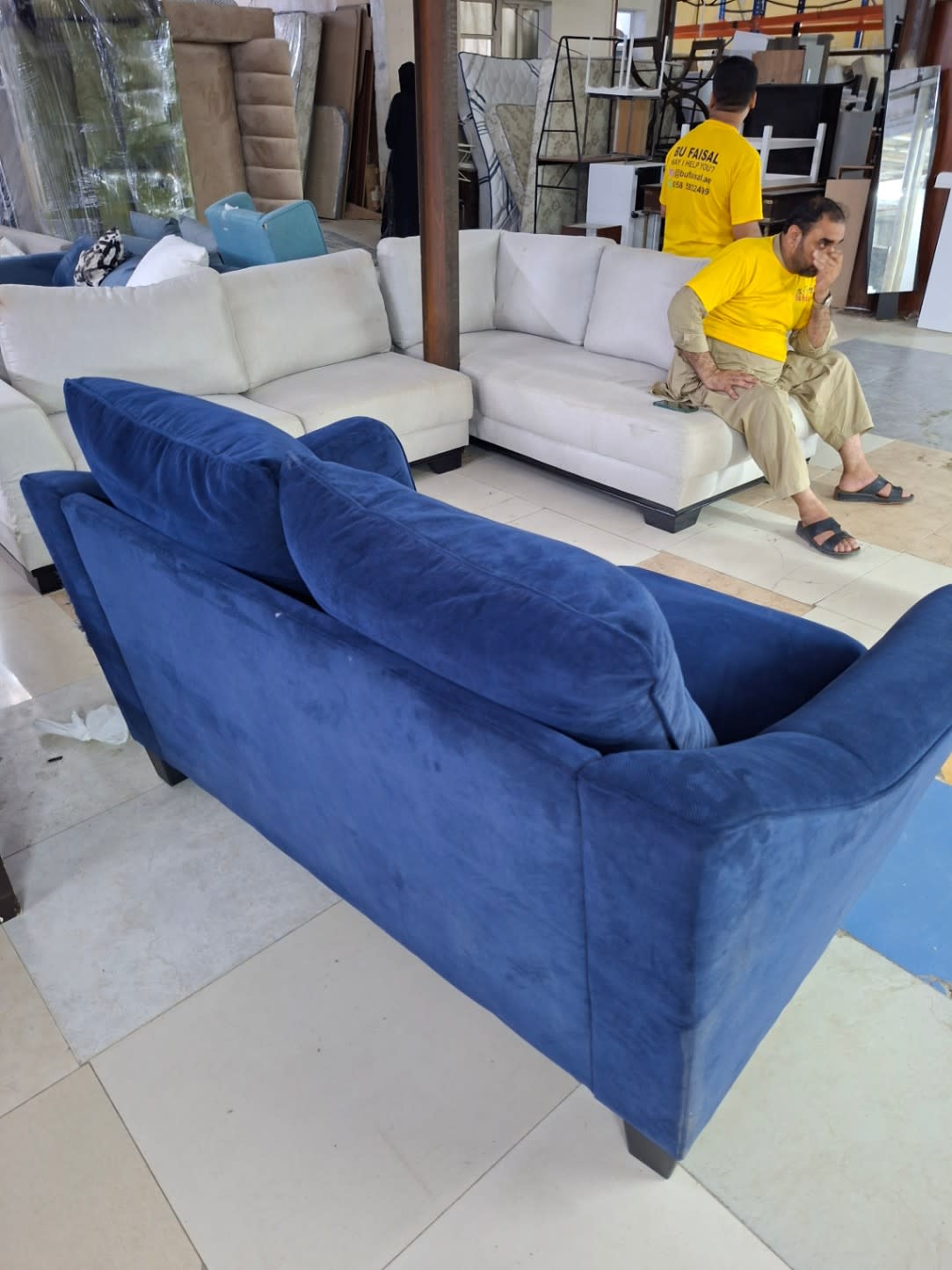 Rear angle of used navy blue 2-seater sofa showing overall fabric wear and condition