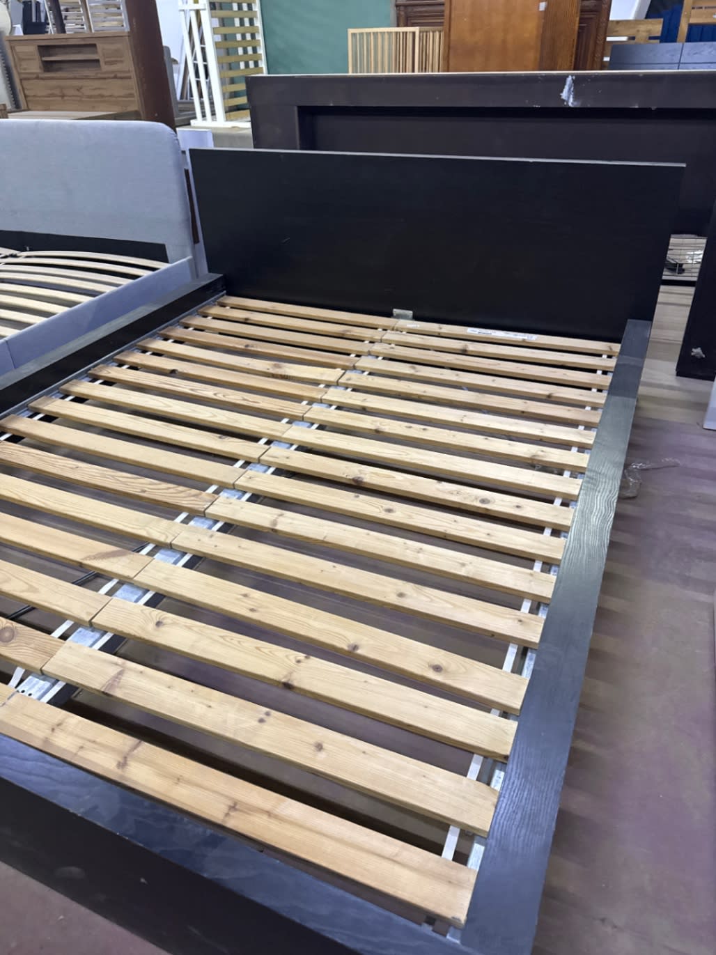 Angle view of used dark brown queen bed frame showing footboard and slatted base at Bufaisal Ajman