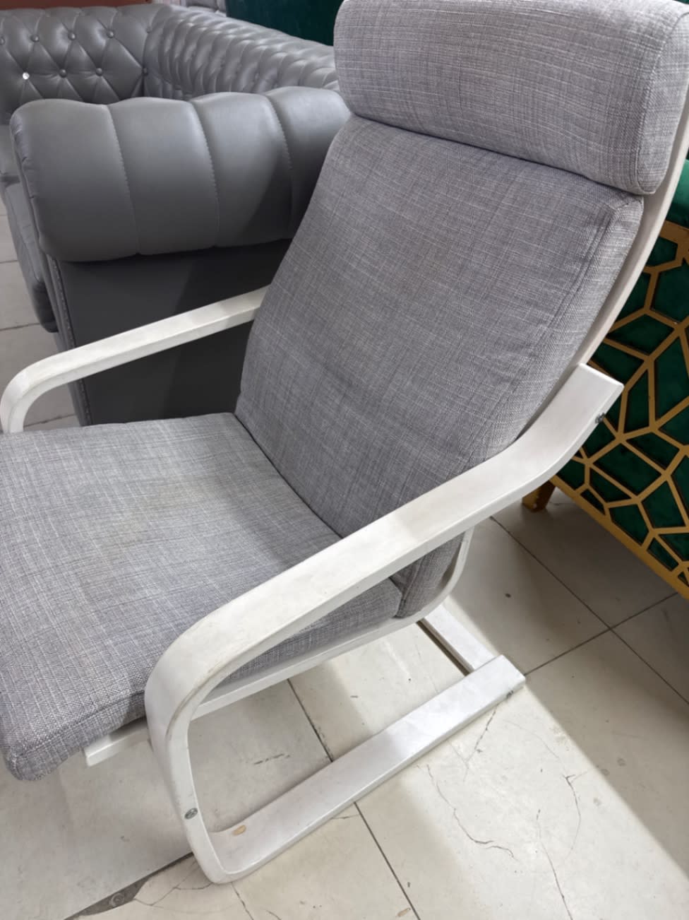 Close-up angle of used grey fabric relaxation armchair white frame at Shop C Ajman Bufaisal