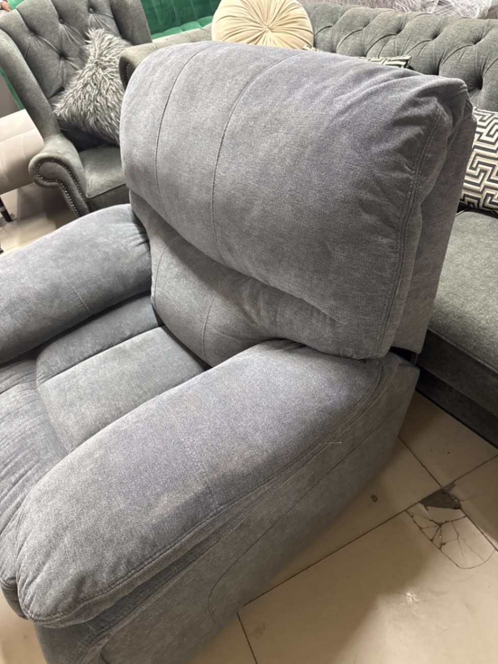 Side profile of used grey fabric recliner armchair in reclined position at Bufaisal Ajman