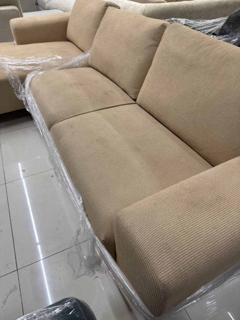 Close-up of seat cushions on new beige L-shape sectional sofa showing clean ribbed fabric condition