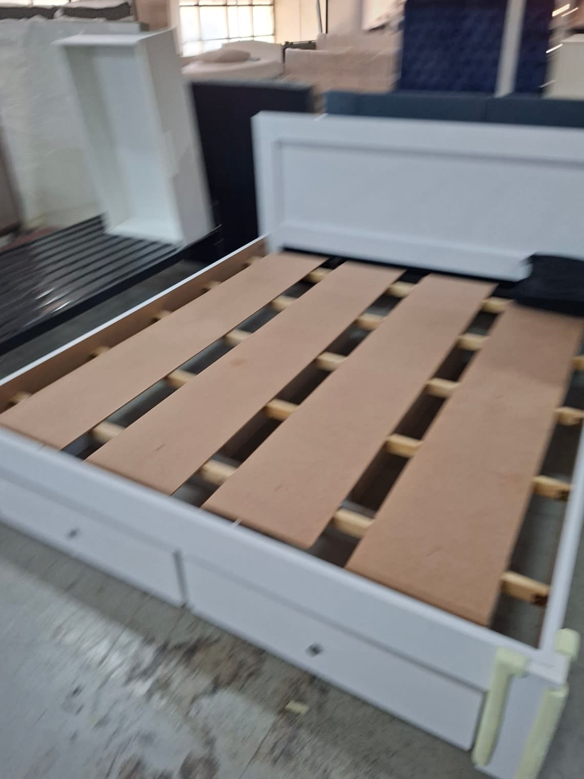 Detail view of used white king bed frame slat system and storage drawer configuration