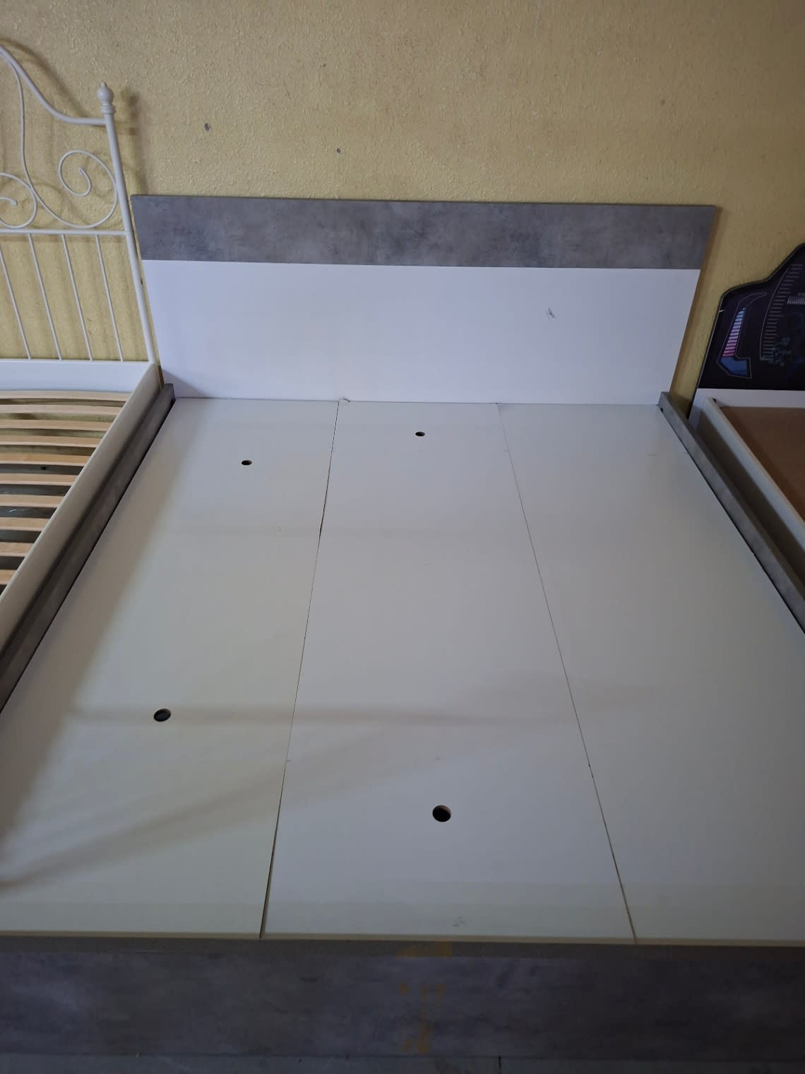 Close-up top view of used queen bed frame storage base panels and grey laminate footboard at Bufaisal Ajman