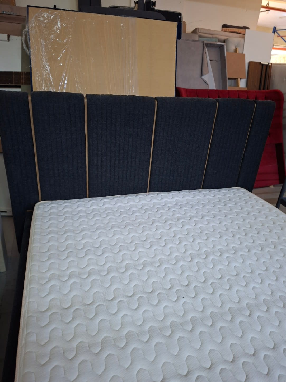 Close-up of charcoal grey vertical panel headboard with gold trim on used king bed frame at Bufaisal Ajman