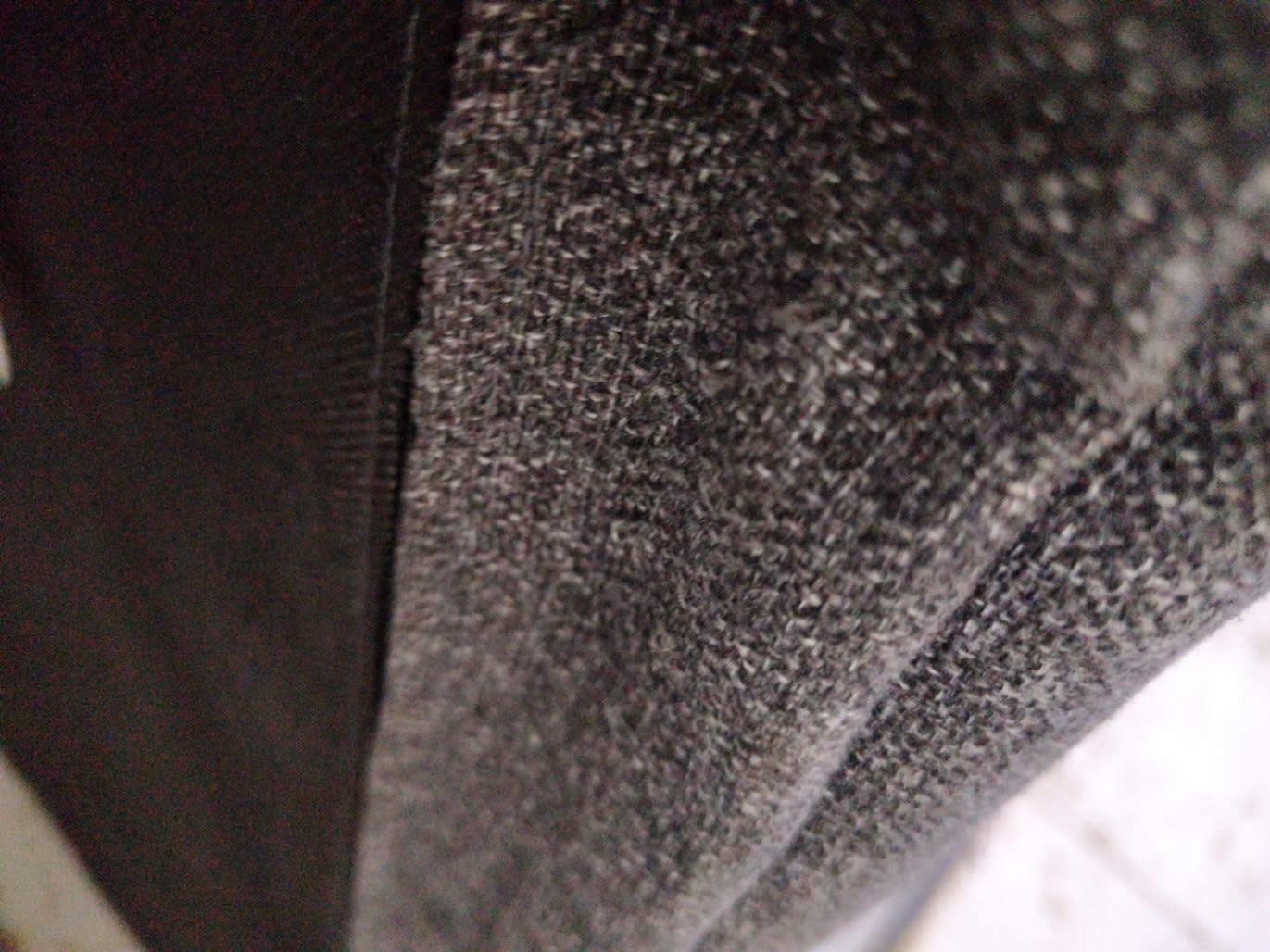 Close-up of dark brown fabric and wood finish detail on used four-poster canopy bed frame