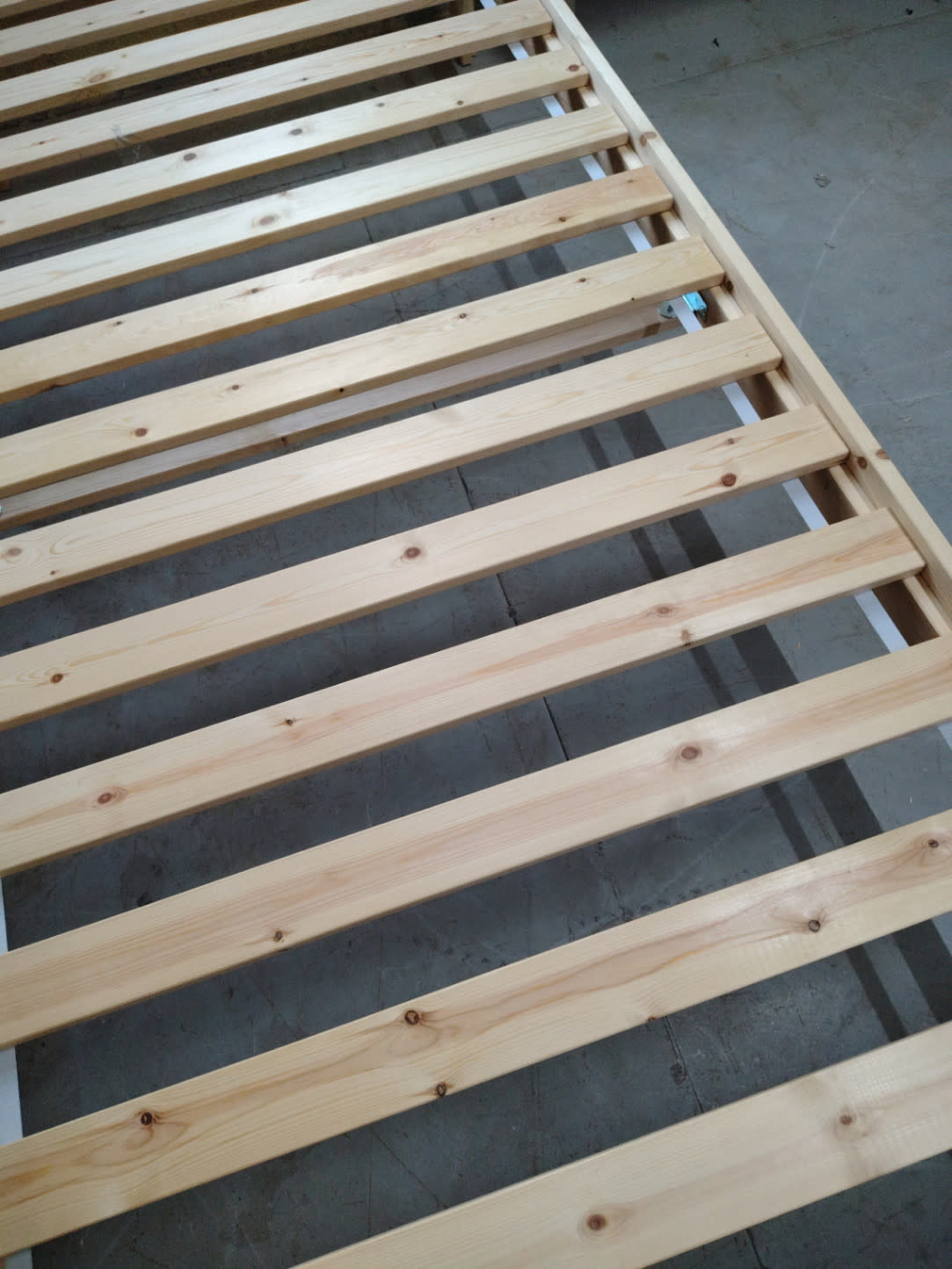 Close-up of natural pine wood slats on used bed frame showing clean condition