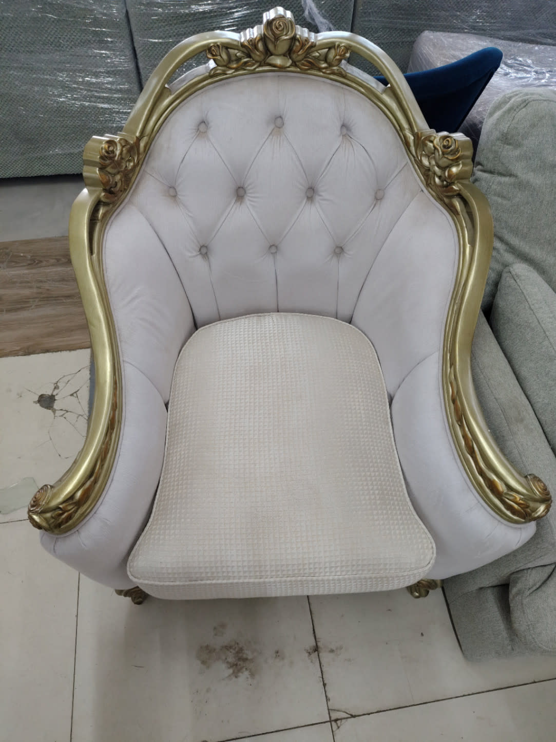 Top-down view of used classic carved armchair showing white tufted back and textured seat cushion