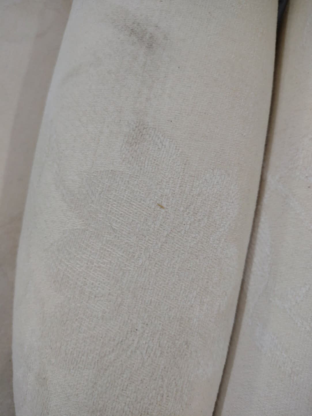 Close-up of armrest on used wingback armchair showing surface soiling and fabric wear