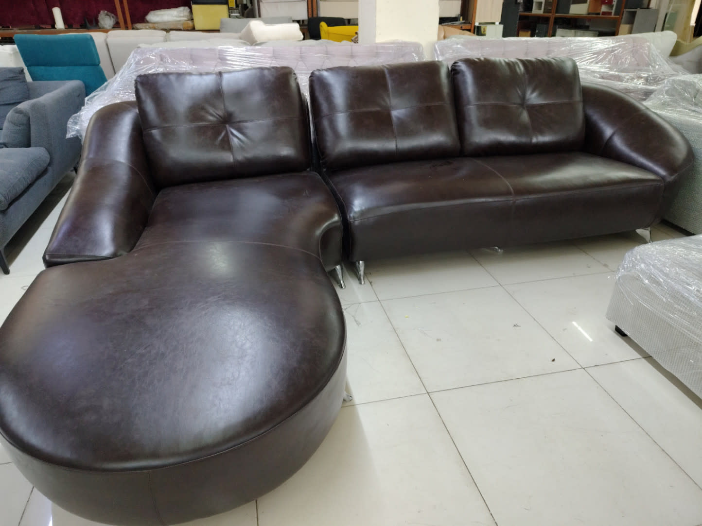 Rear angle of used dark brown L-shape sectional sofa showing tufted backrest and chrome legs