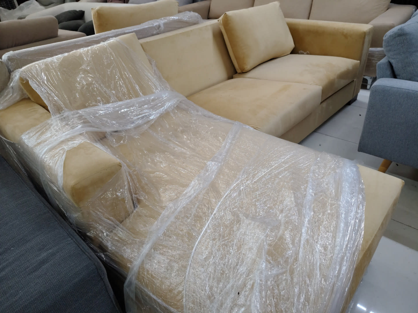 Side angle of new beige L-shape sectional sofa with chaise partially wrapped at Bufaisal Shop C Ajman