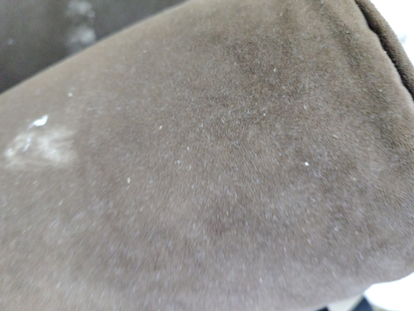 Close-up of fabric detail on used wide armchair showing visible staining and surface soiling