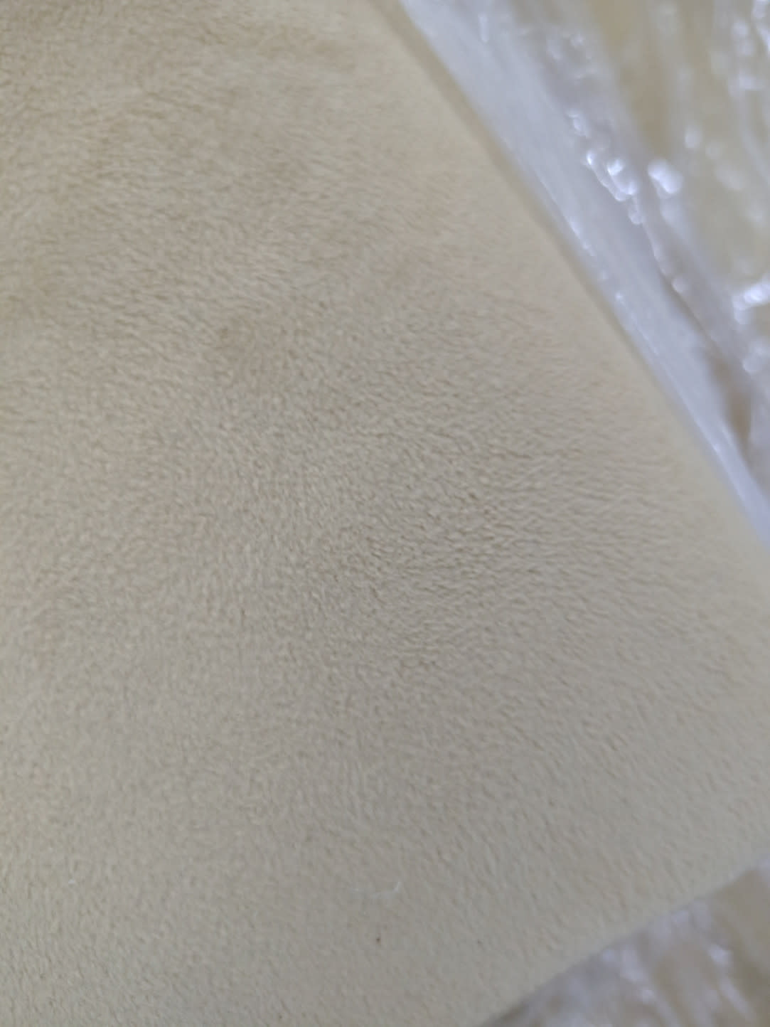 Close-up of beige velvet fabric texture on new L-shape sectional sofa at Bufaisal Ajman