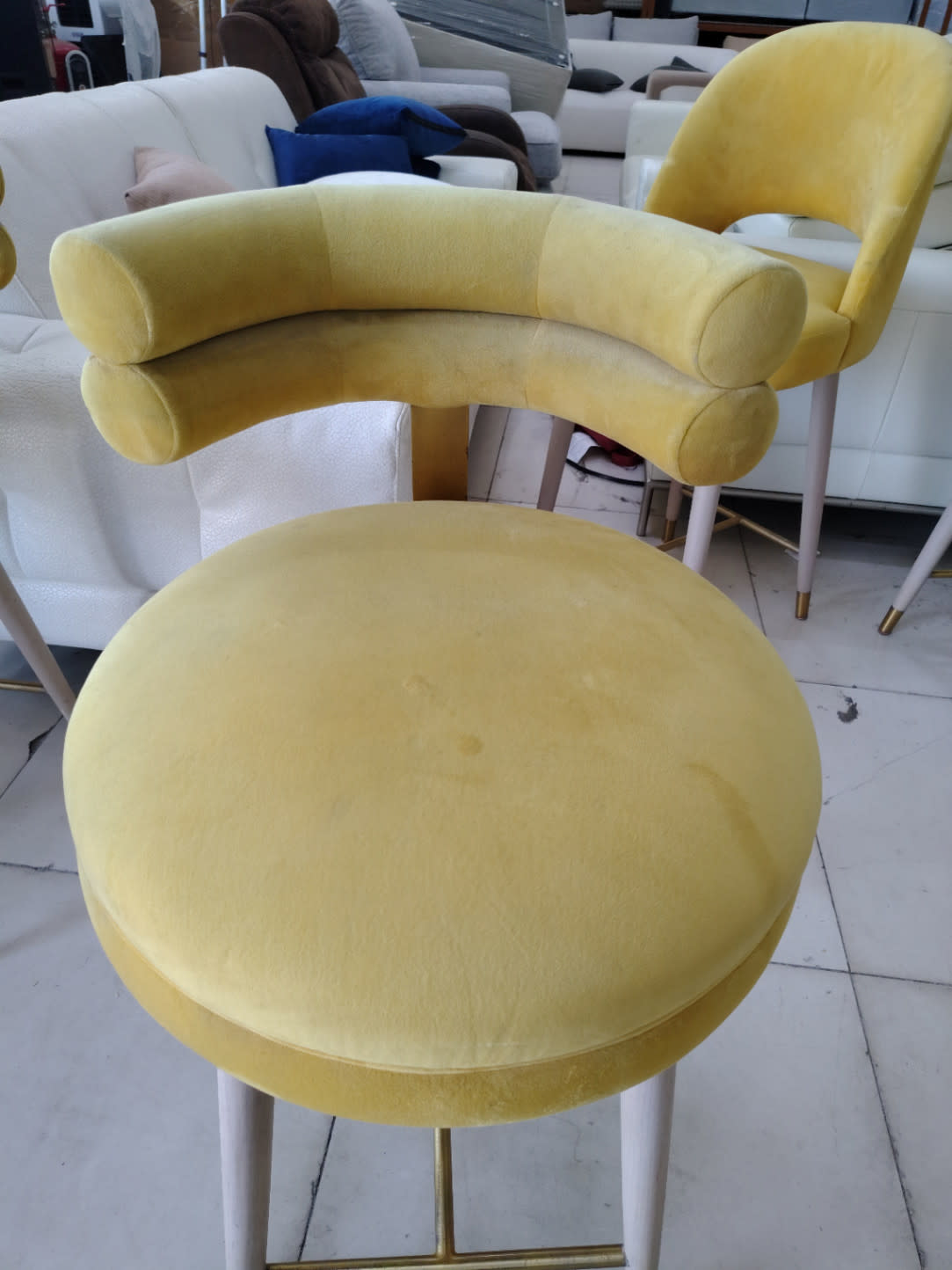 Top-down view of used yellow velvet bar stool seat showing light surface marks at Bufaisal Ajman