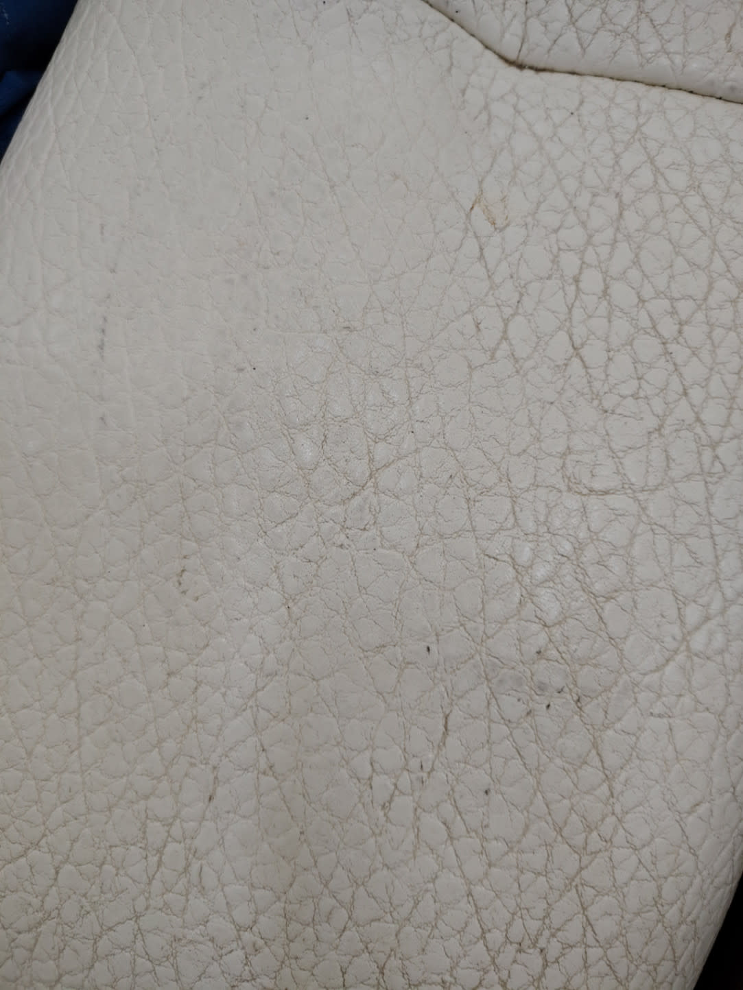 Close-up of faux leather surface on used 3-seater sofa showing cracking and crazing condition