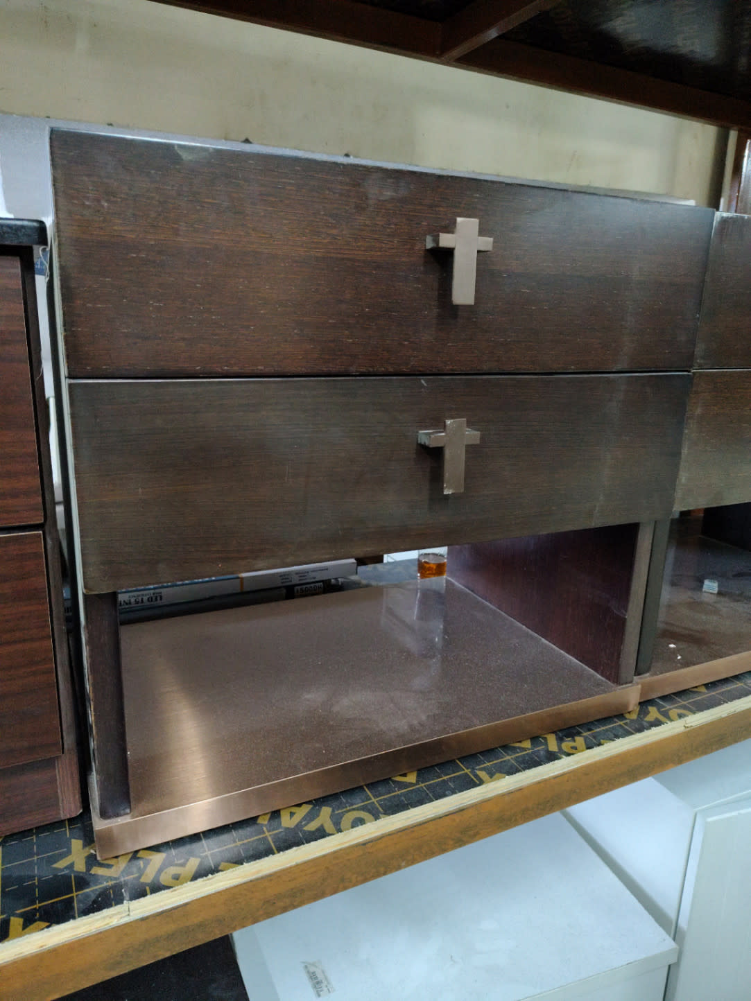Side angle of used 2-drawer nightstand showing brushed metal open shelf and drawer condition