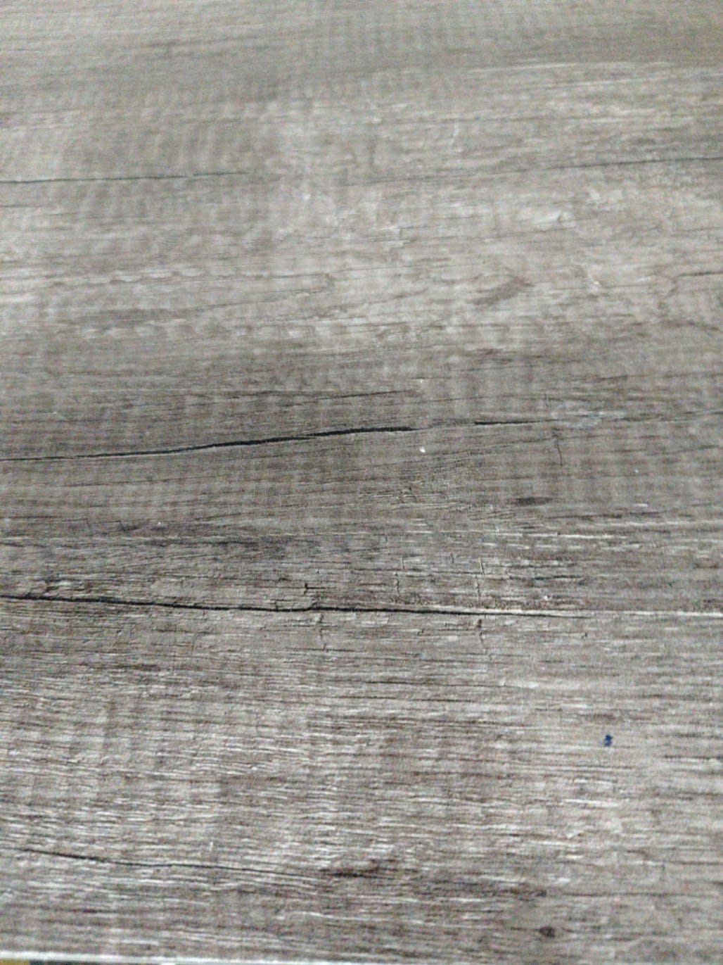 Close-up of grey laminate top surface of used nightstand showing visible scratches and surface cracks
