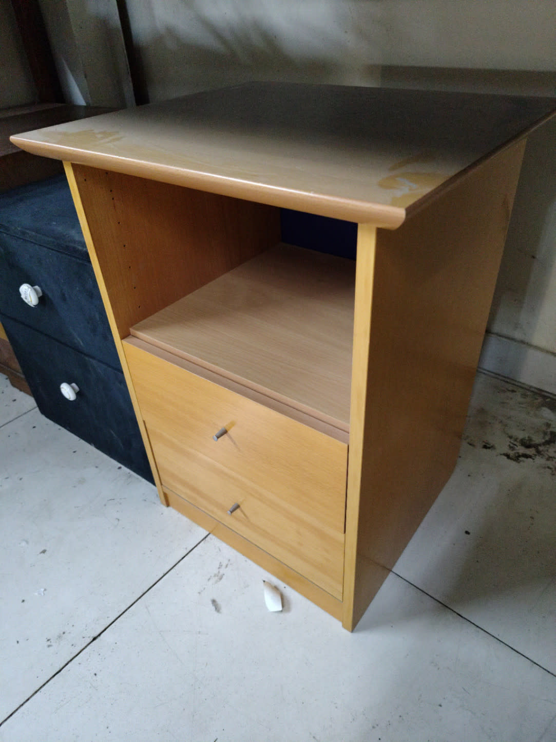 Side angle view of used light oak nightstand with shelf and two drawers at Bufaisal Ajman