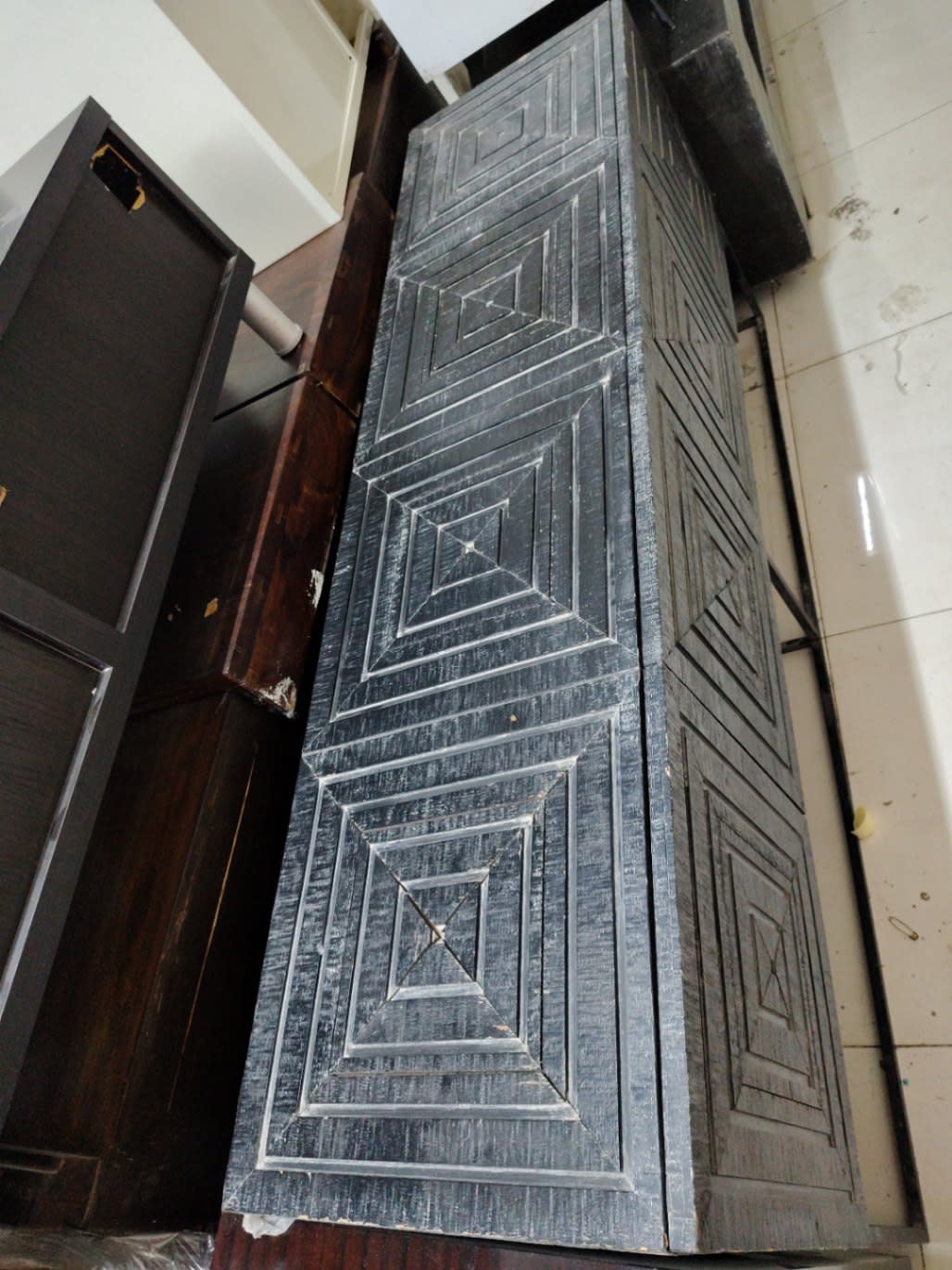 Side angle view of used dark grey sideboard cabinet showing carved door detail and metal base frame