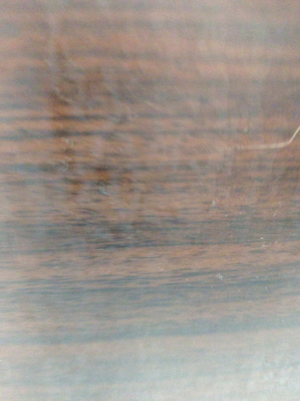 Close-up of dark brown wood finish surface on used TV stand showing wear and staining