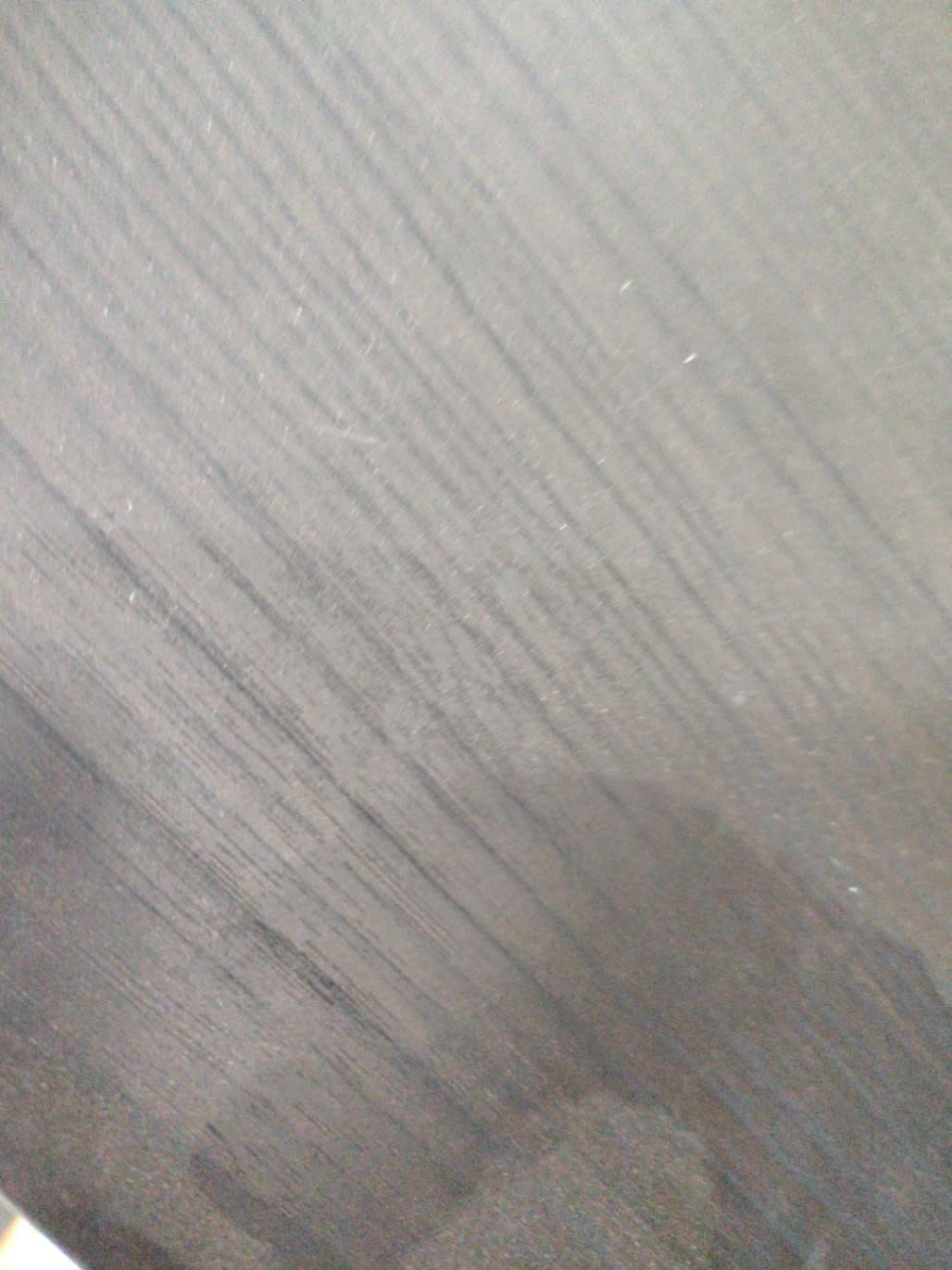 Close-up of top surface of used dark brown TV stand showing light scratch marks