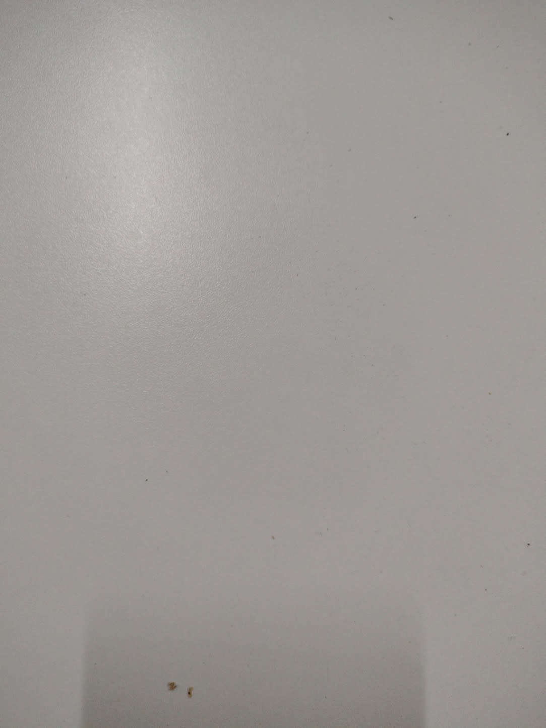 Interior surface detail of used white dressing table showing minor specks on cabinet base