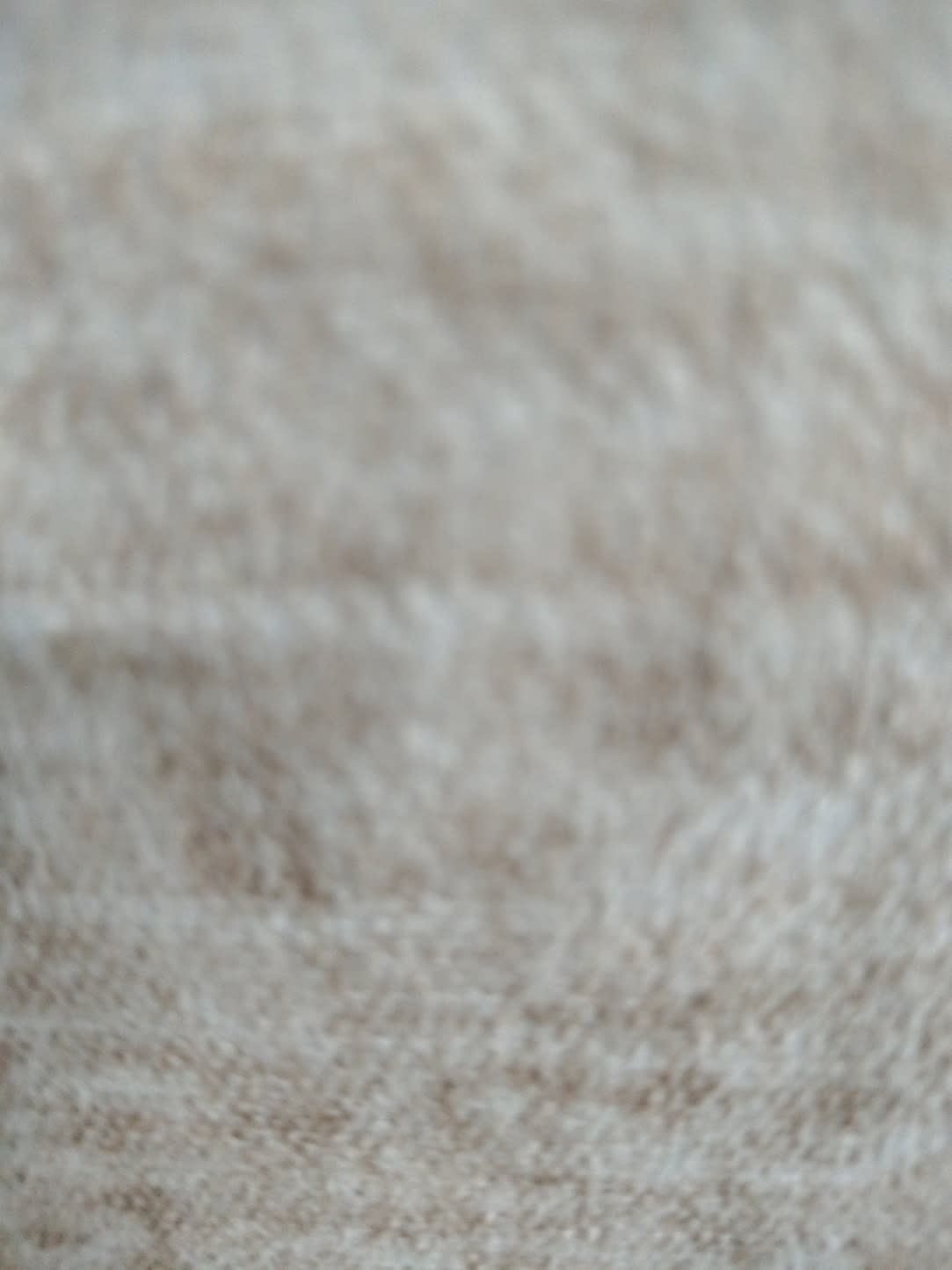 Close-up of beige fabric upholstery on used storage ottoman showing texture and surface condition