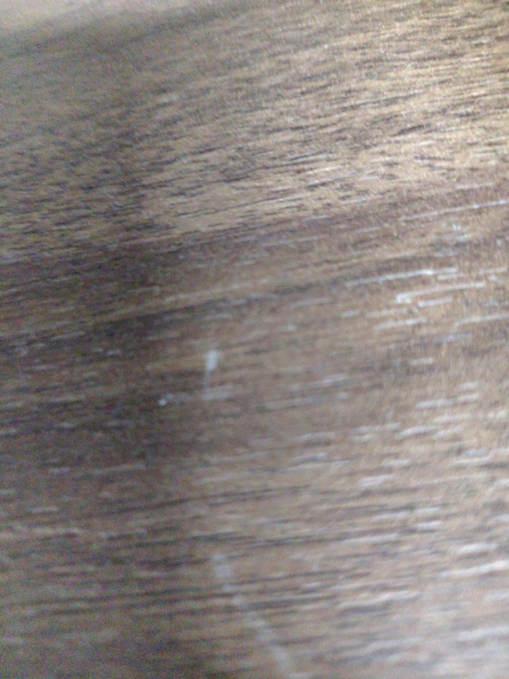 Close-up of brown wood-finish top surface of used nightstand showing surface scratches
