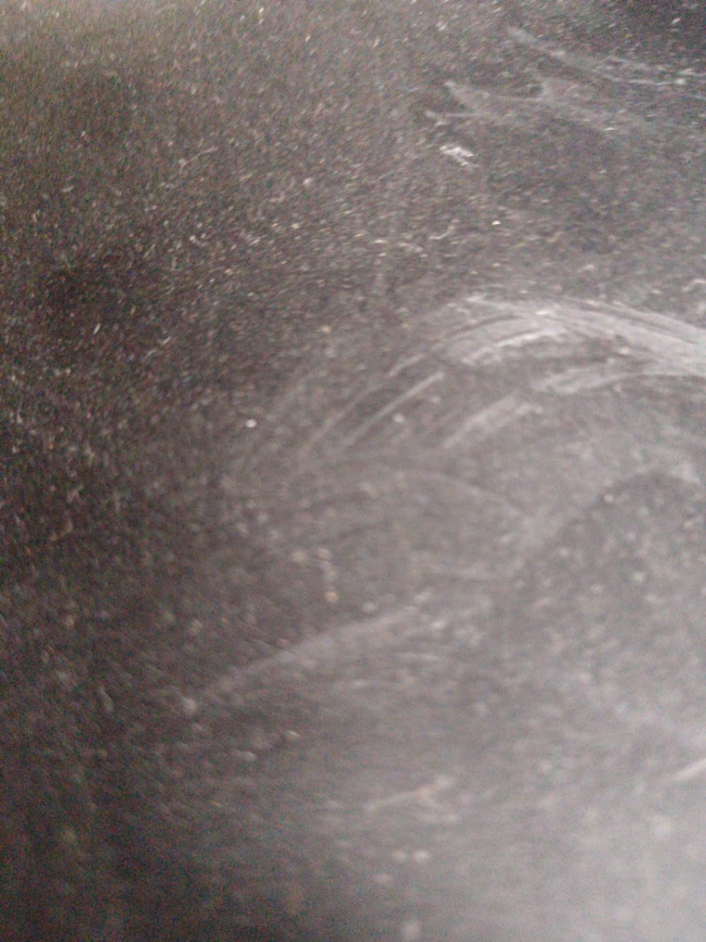 Close-up of surface scratches and abrasion marks on used black metal nightstand