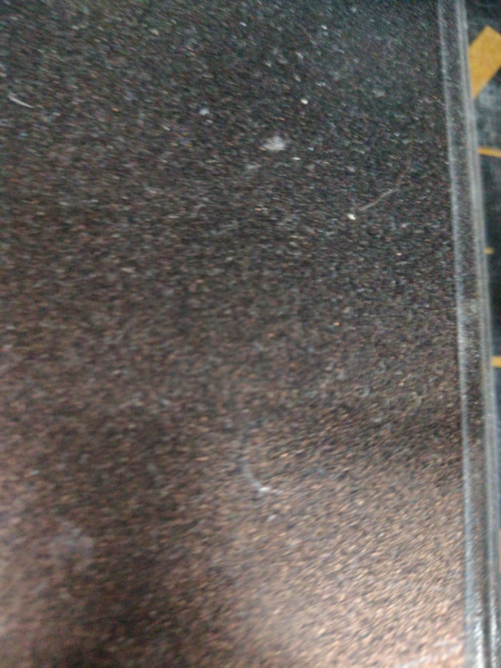 Close-up of dark bronze nightstand surface showing light scratches consistent with good condition