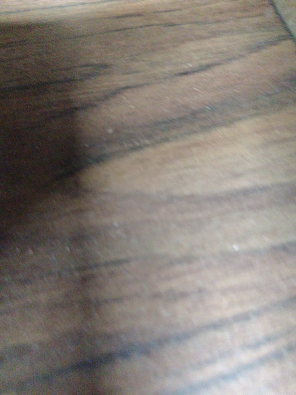 Close-up of walnut brown laminate surface on used nightstand showing minor scuffs