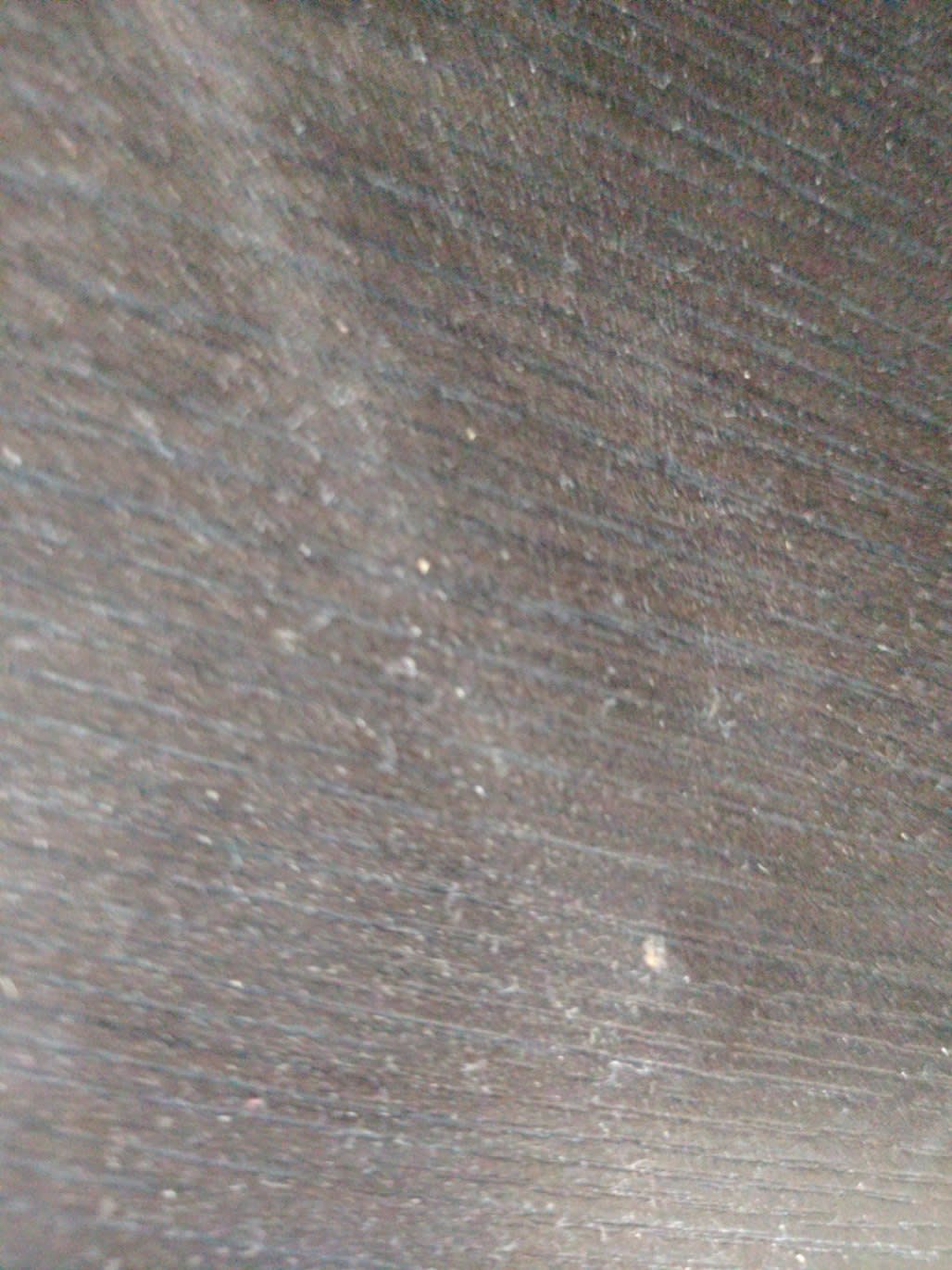 Close-up of surface showing scratches and scuff marks on used dark brown nightstand