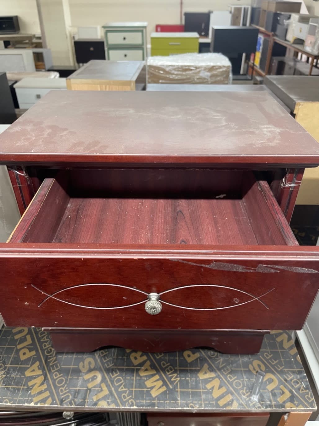Top-down view of used mahogany 2-drawer nightstand with upper drawer open showing top surface wear