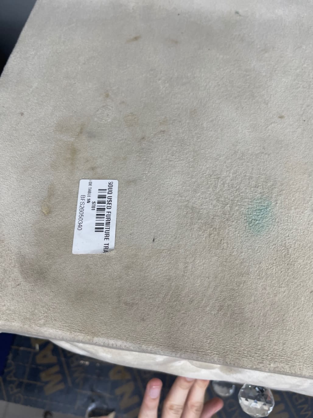 Bufaisal barcode label BFS26050340 on top of used cream upholstered nightstand showing staining