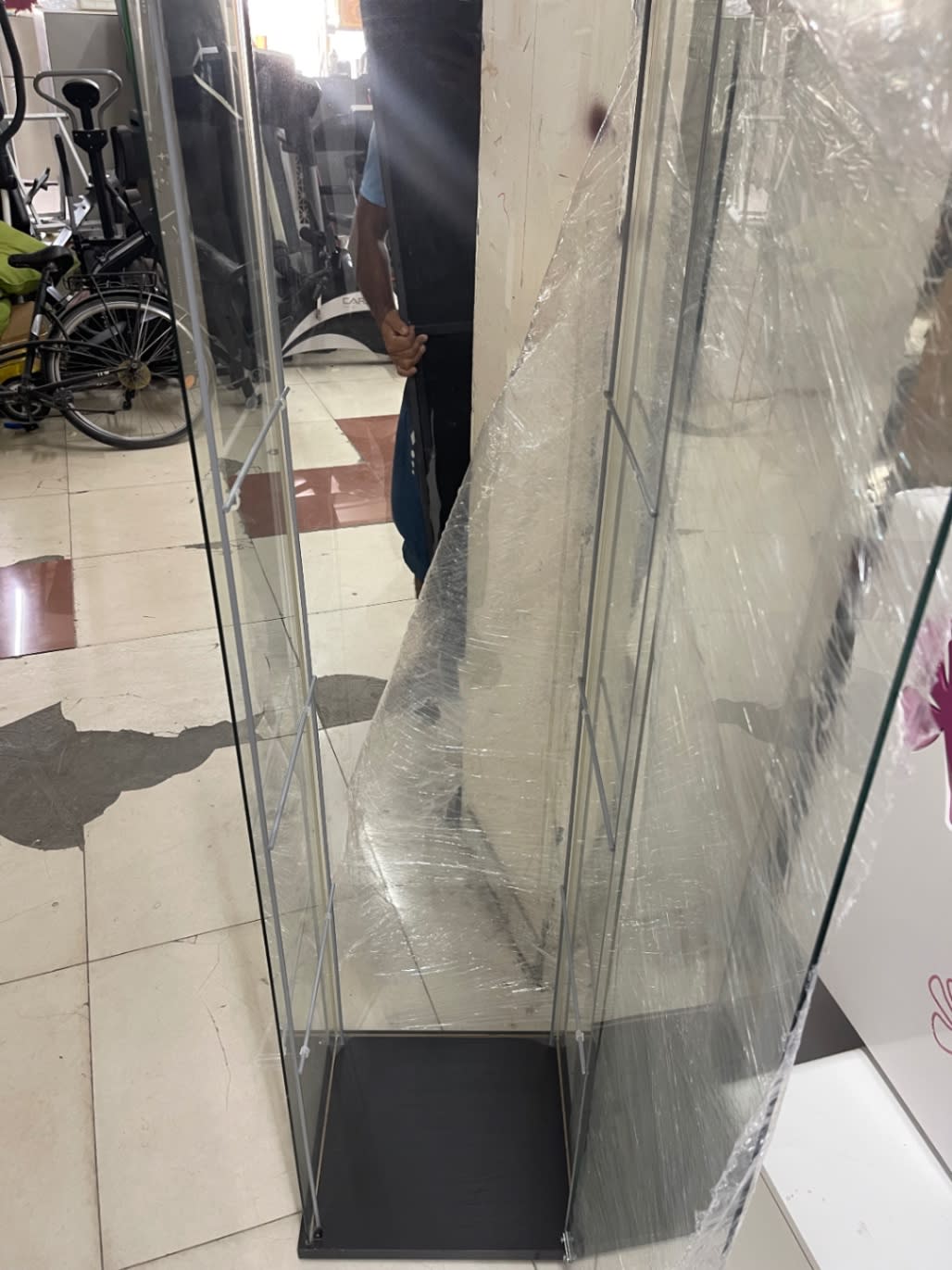 Interior base view of used glass display cabinet tower showing black base and shelf supports