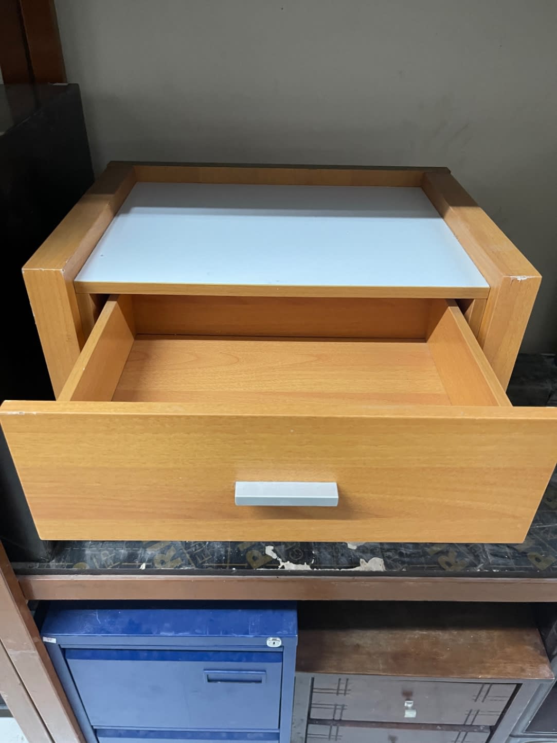 Upper drawer open on used light oak bedside nightstand showing clean drawer box
