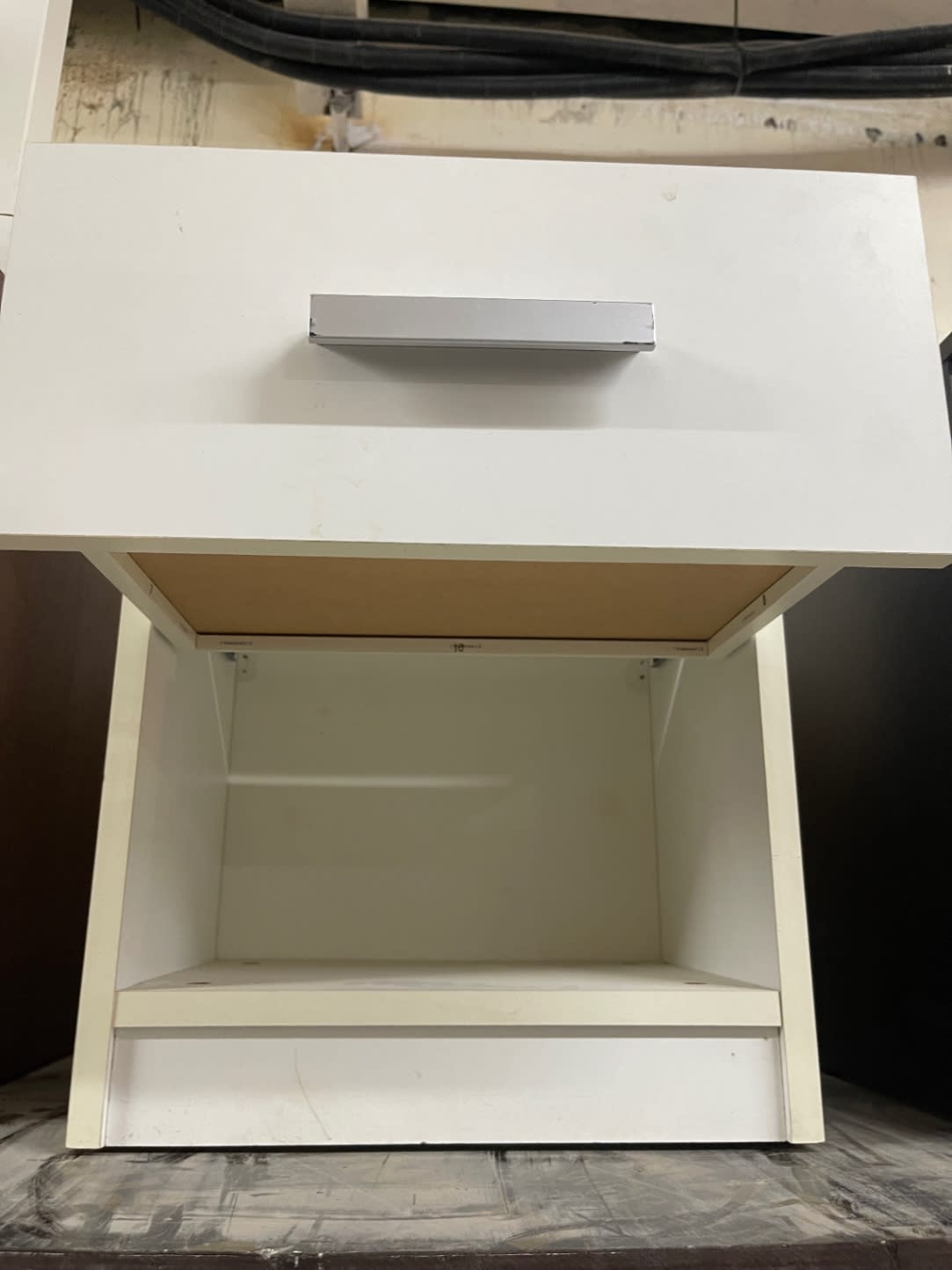 Top-down view of used white bedside nightstand showing open shelf interior and drawer underside