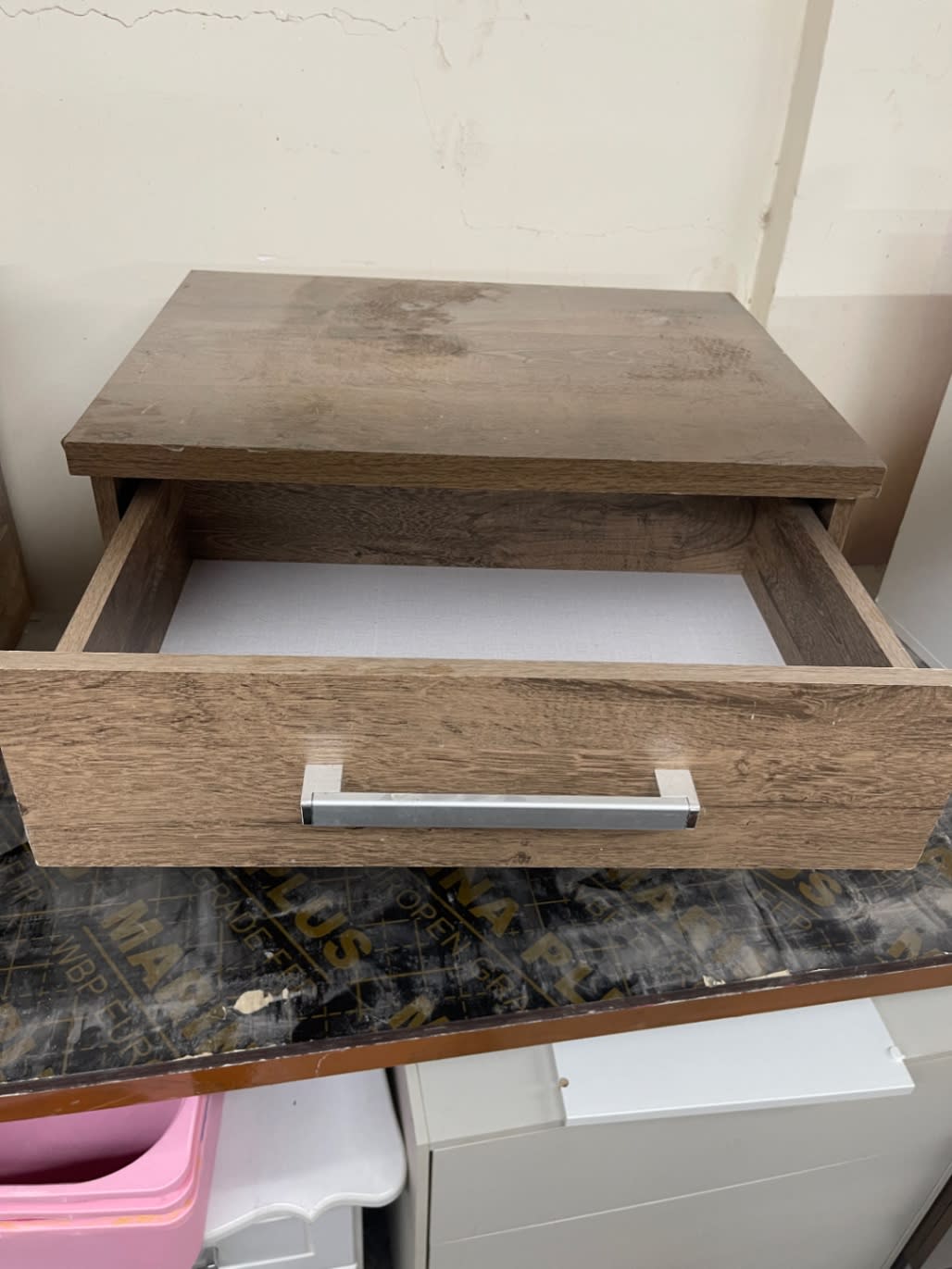 Upper drawer open on used 2-drawer nightstand showing top surface dust marks