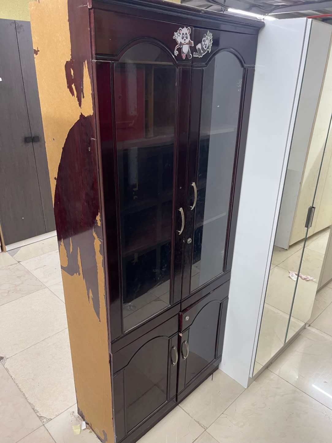 Side panel of used glass-door display cabinet showing significant laminate peeling on left side