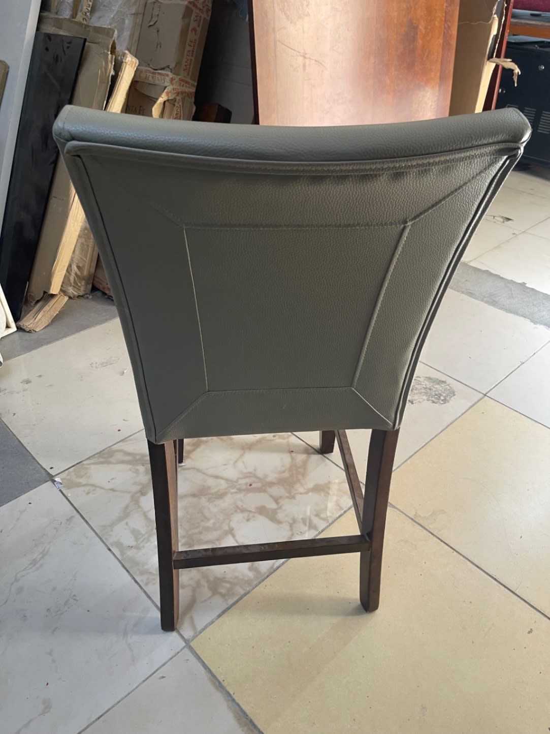 Rear view of used counter-height bar chair showing leatherette back panel and dark walnut wood legs