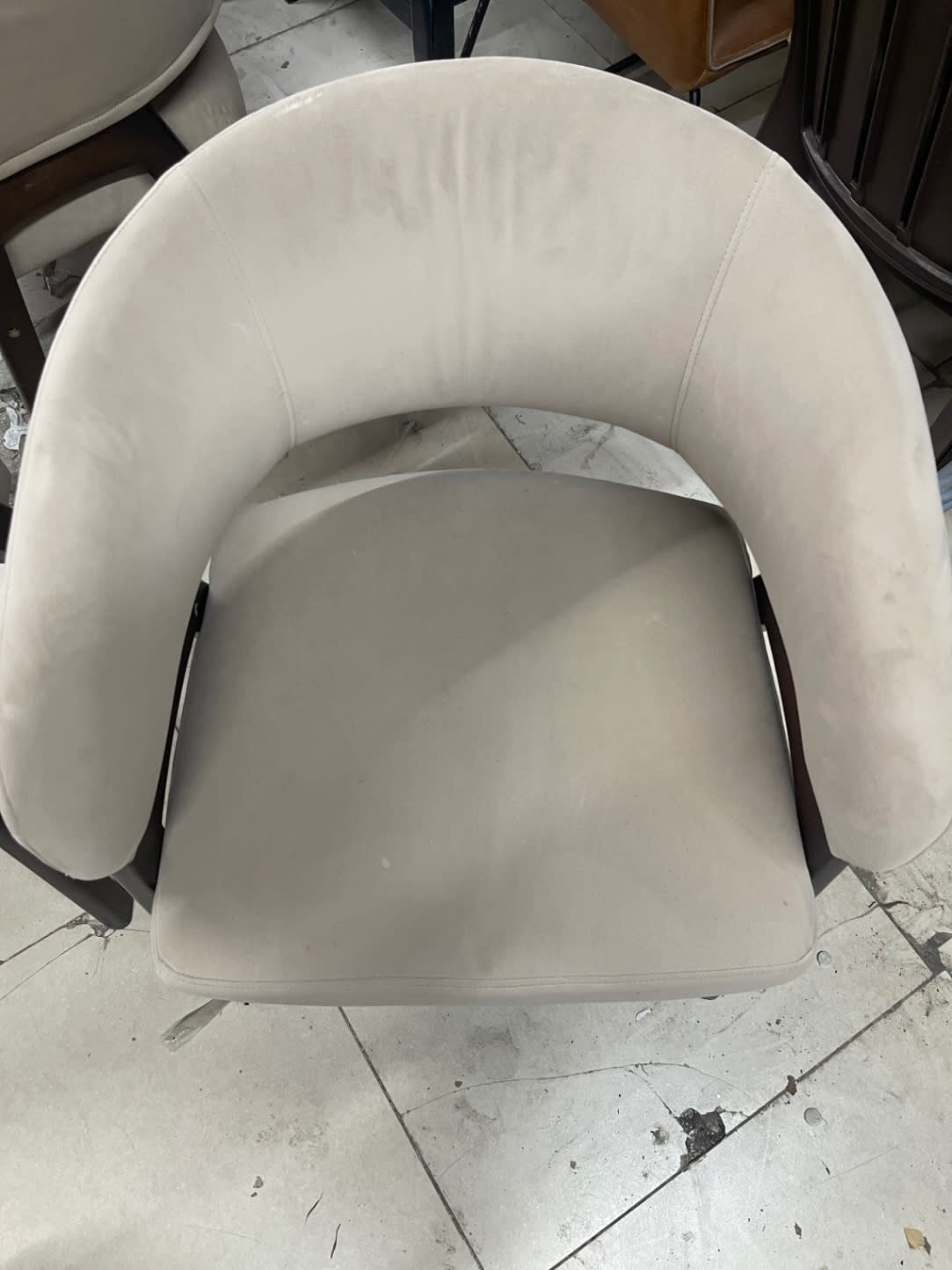 Top-down view of used beige barrel accent chair seat showing light surface soiling