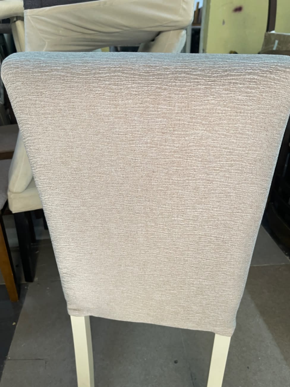 Rear view of new upholstered dining chair showing beige woven fabric back panel at Bufaisal Ajman