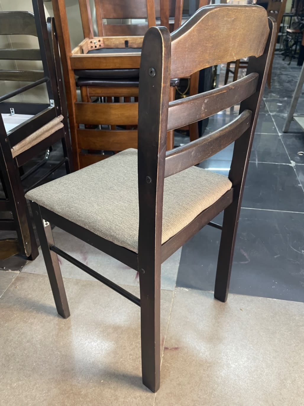 Rear view of new ladder-back dining chair showing dark walnut frame and beige seat Bufaisal Ajman