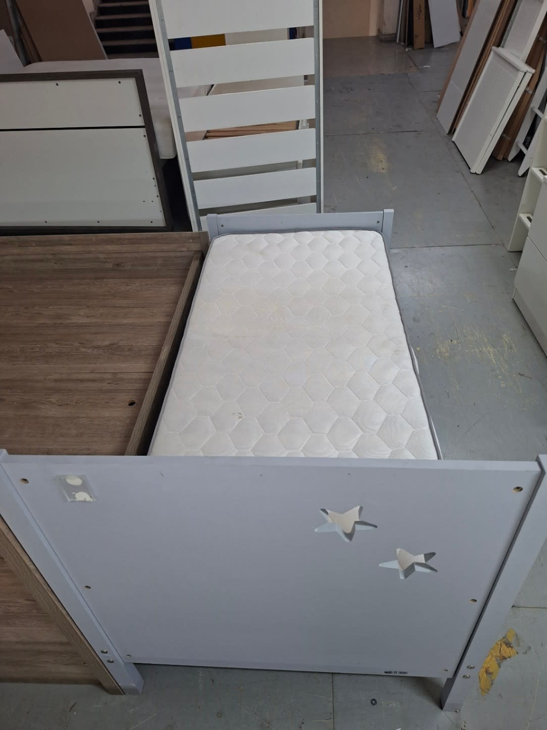 Foot-end view of used grey kids single bed frame with star motif detail and included mattress