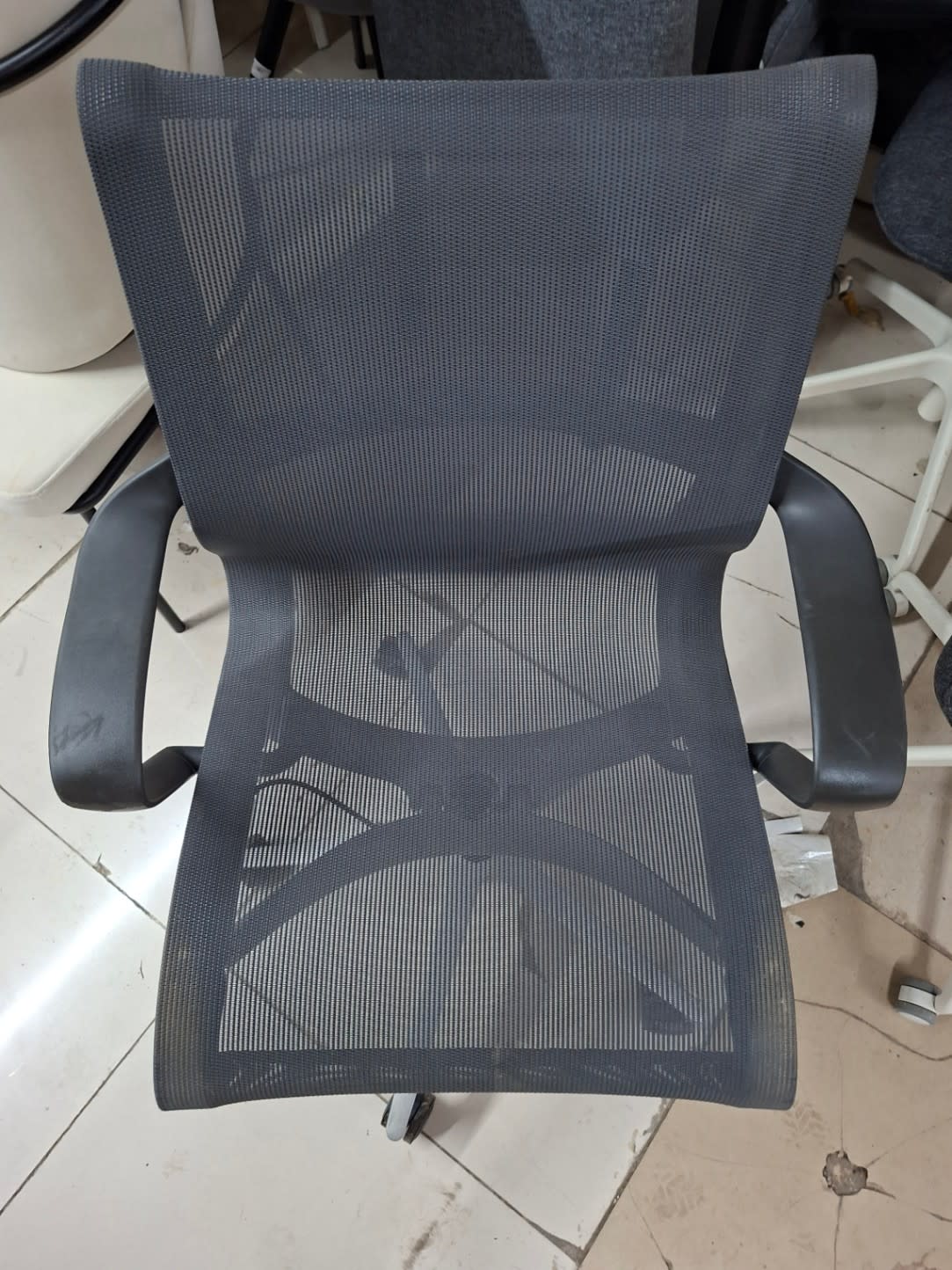 Top-down view of used grey mesh office chair seat and armrests showing good condition