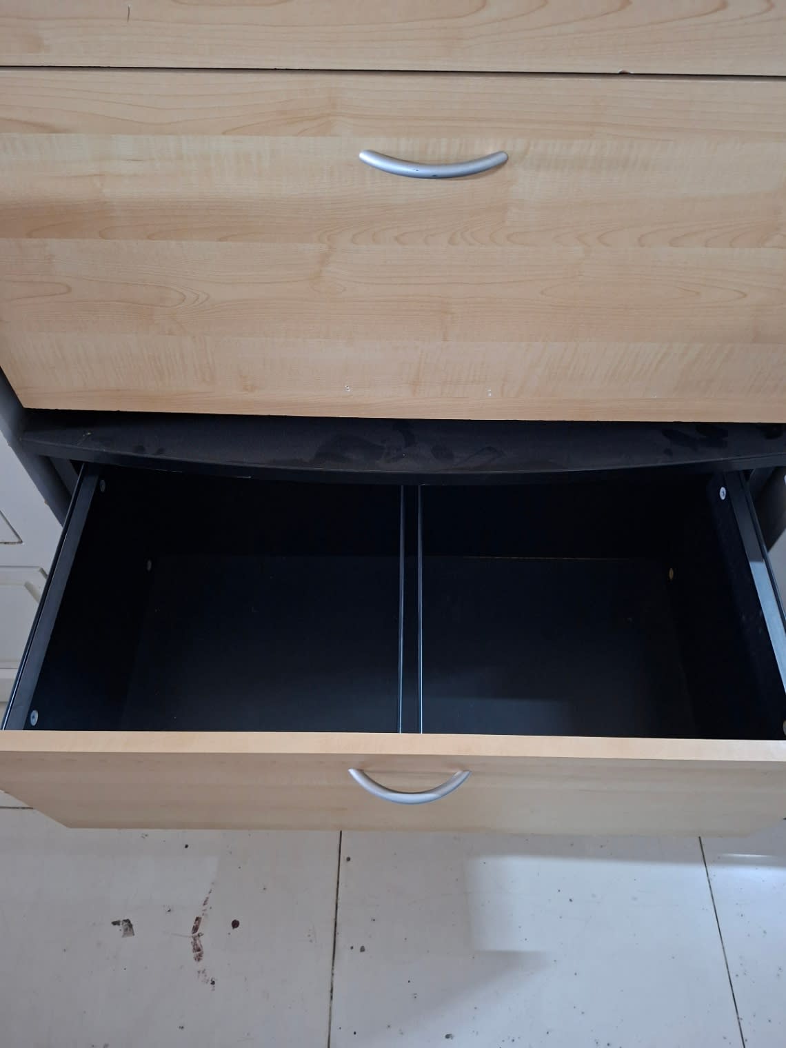 Open drawer interior of used 5-drawer chest of drawers showing divider and clean black lining